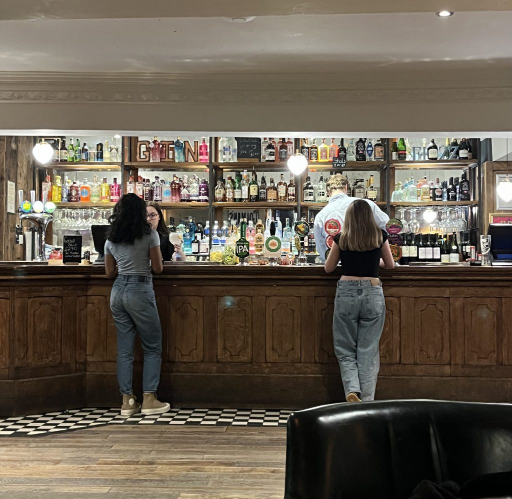 Two Friends Stood Apart at a Bar